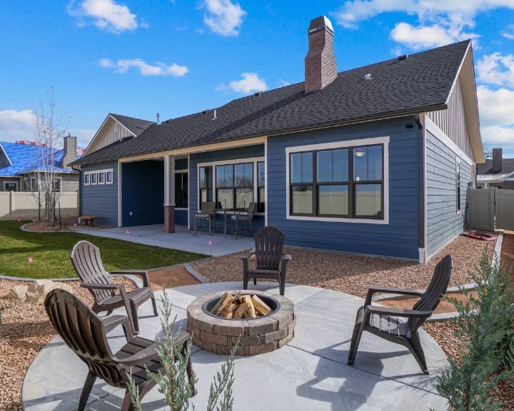 A city backyard with a concrete patio hosting a fire pit and chairs.