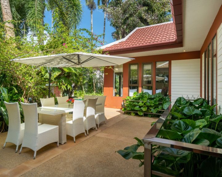 A city concrete patio adorned with white furniture and an umbrella.