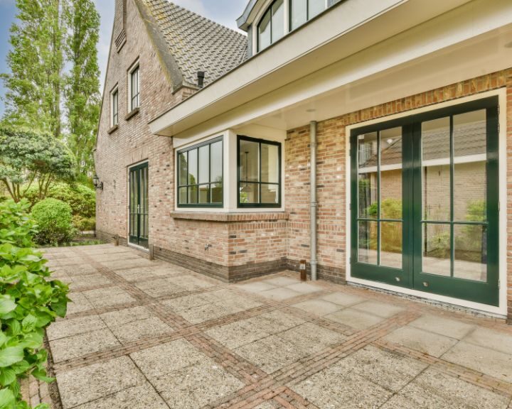 A city house featuring a patio with concrete slabs and vibrant green doors.